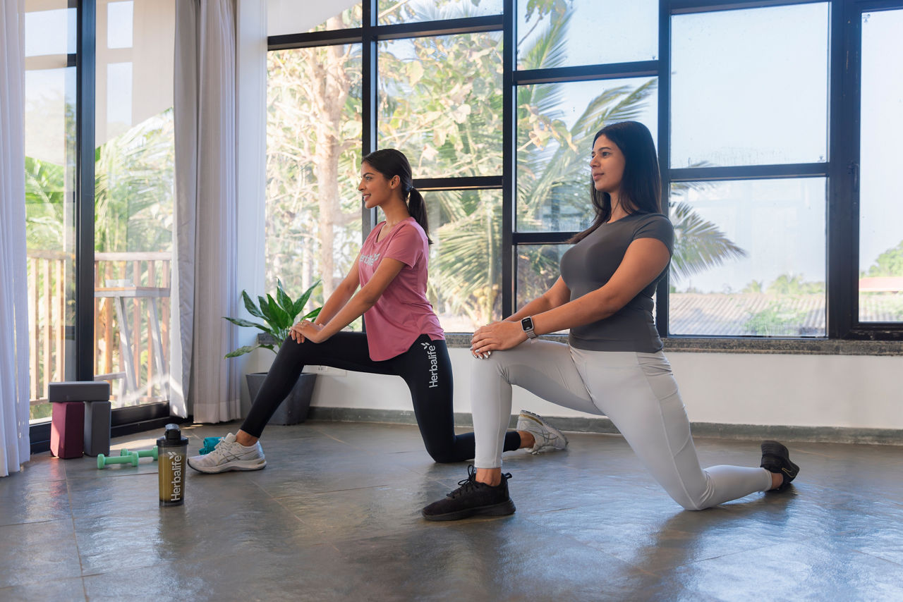 Two women stretching in a brightly lit room