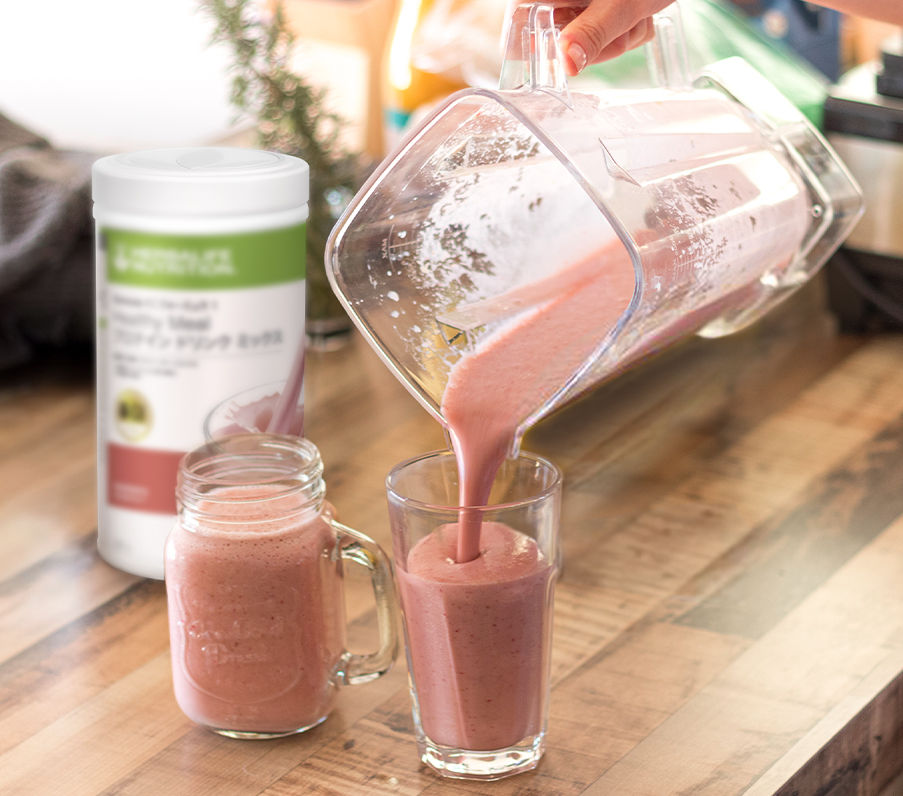 Herbalife Formula 1 strawberry shake being poured from blender into a glass and a jar.