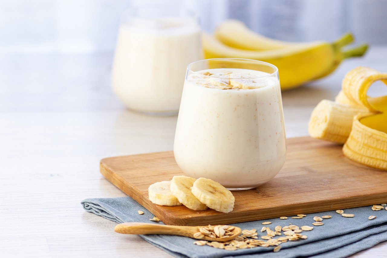 A protein shake made with banana and oatmeal on a cutting board