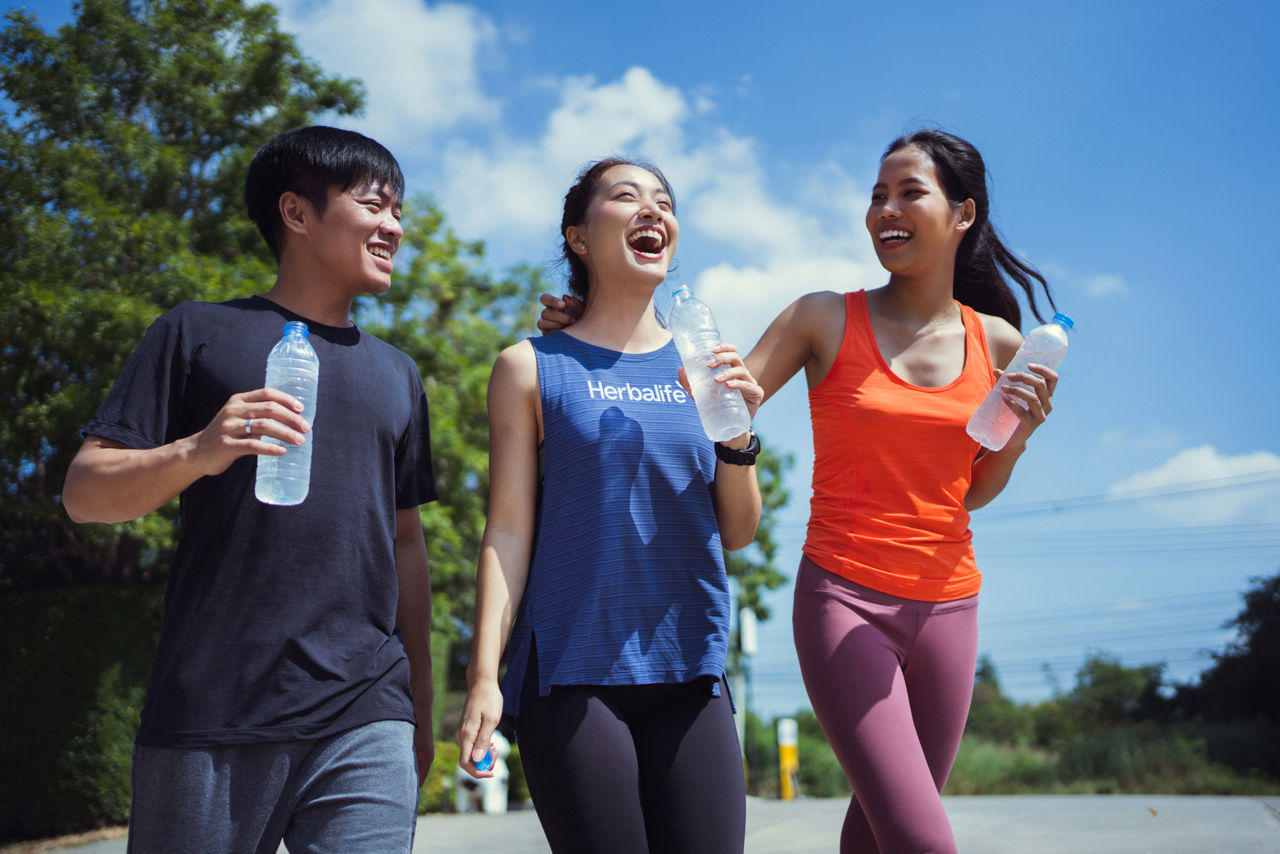 Three friends rehydrating after exercising outdoors