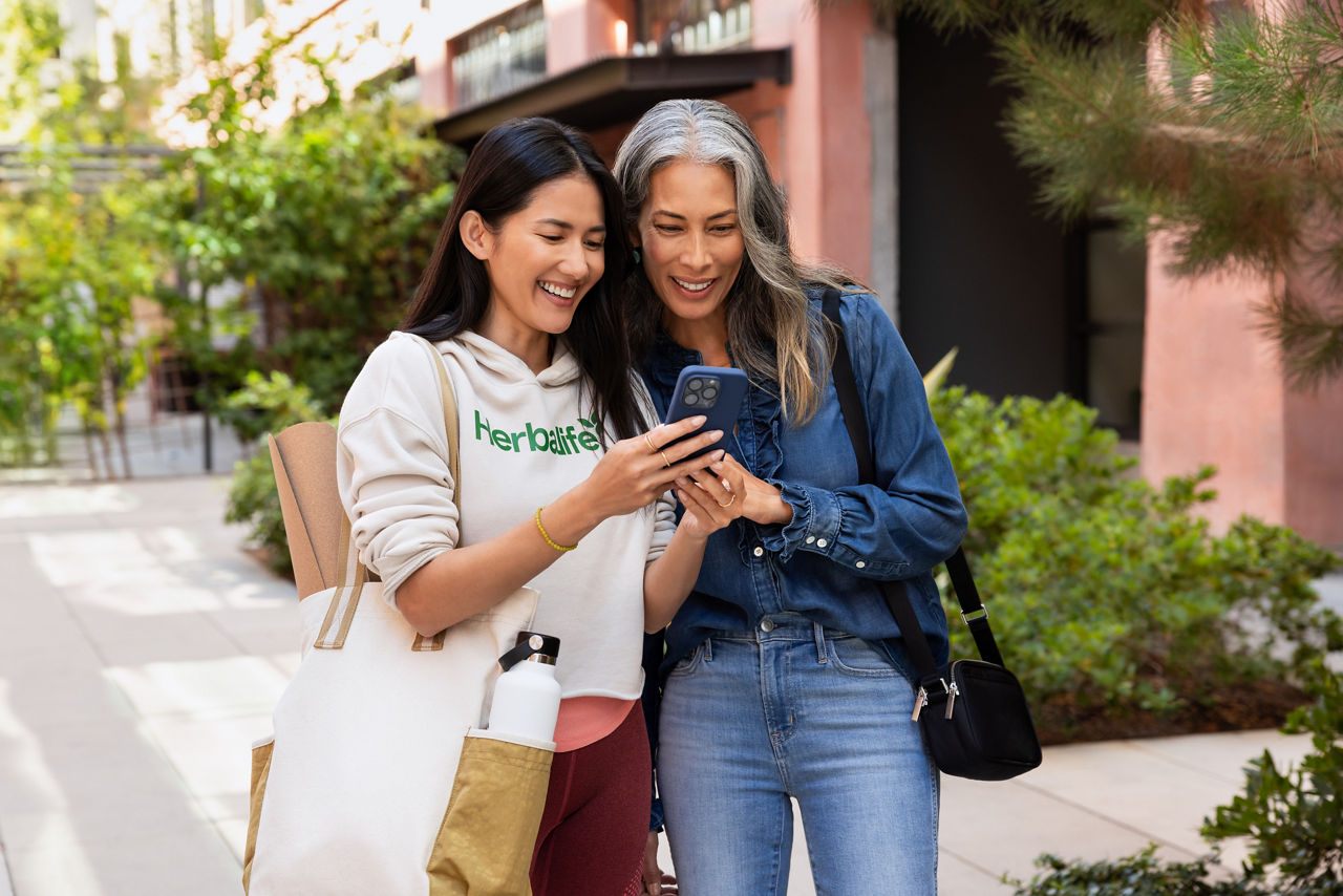 Two women smiling while looking at a cell phone