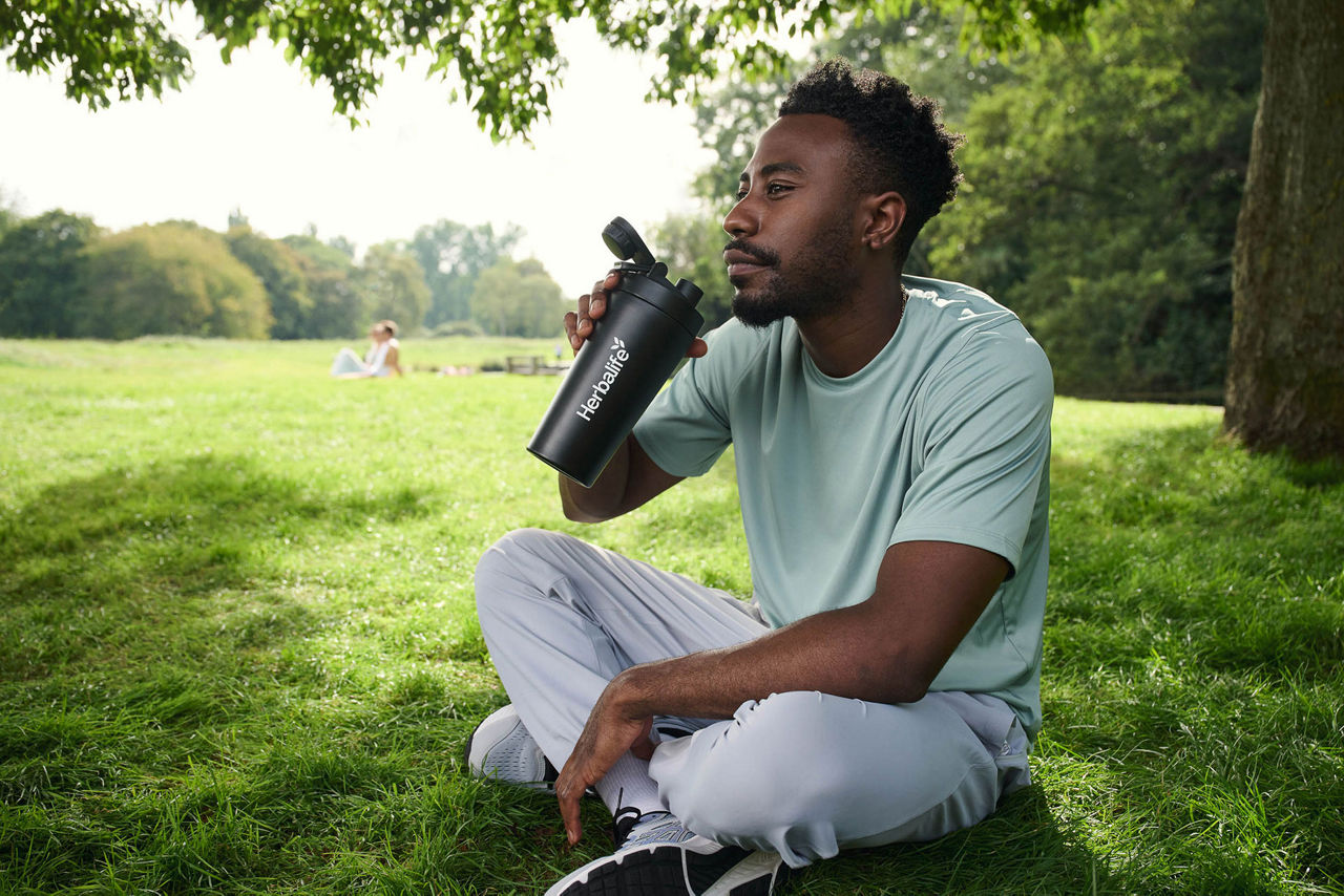čovek pije šejk u parku