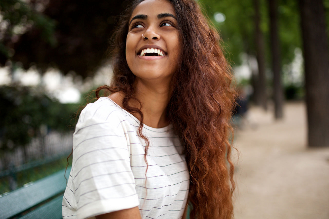 Close up portrait of beautiful young indian woman laughing in park