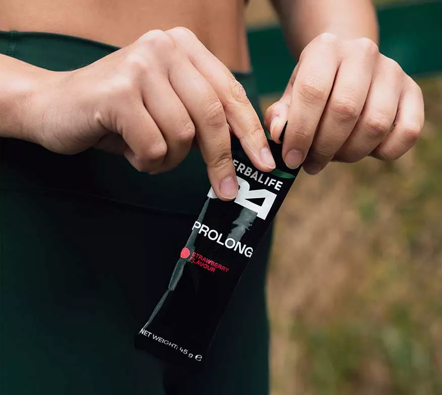 A woman holding a Herbalife24 Prolong energy gel.